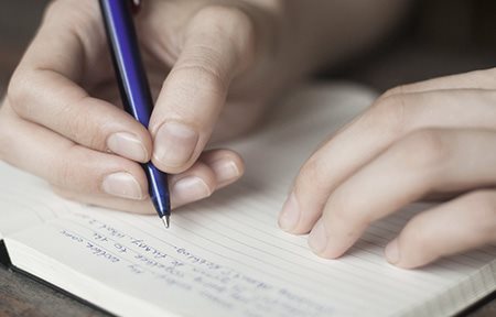 Fotografía de una mujer escribiendo un diario con los disparadores