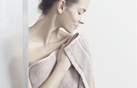Una mujer secándose la piel con palmaditas después de la ducha.
