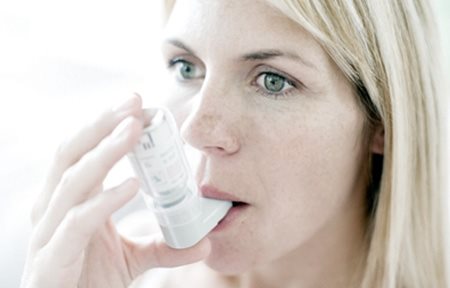 Una mujer utilizando un inhalador.