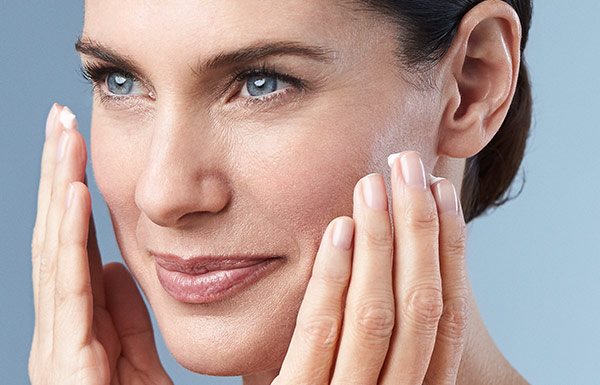 Una mujer aplicando crema en su rostro.