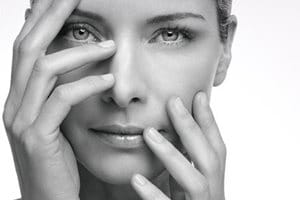 Una mujer alza las manos delante de su rostro.