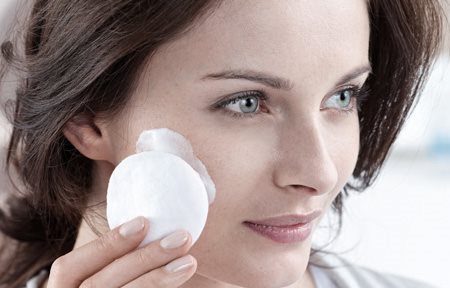 Mujer limpiándose la cara con una gasa de algodón