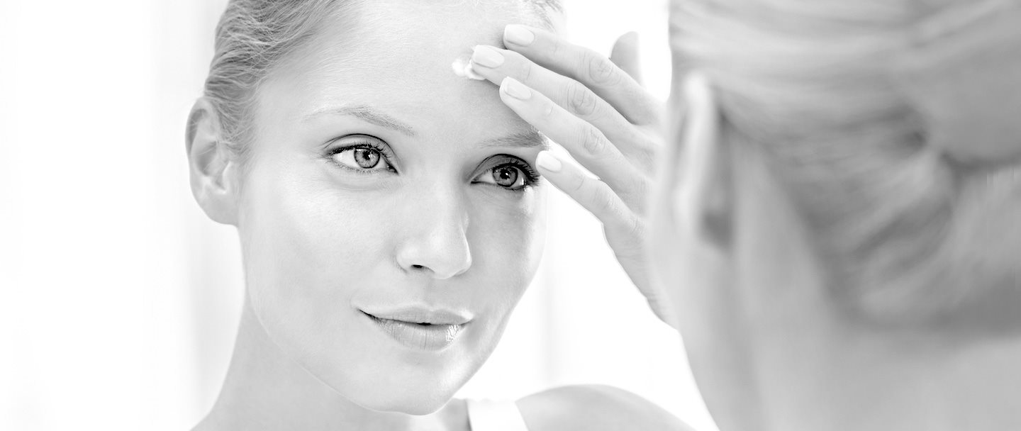 Mujer aplicando crema sobre su frente